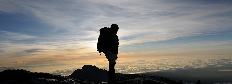 At sunset hiker at the summit of Mount Kilimanjaro