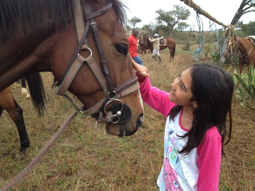 A girl strokes her horse at Borana Riding, Laikipia, Kenya
