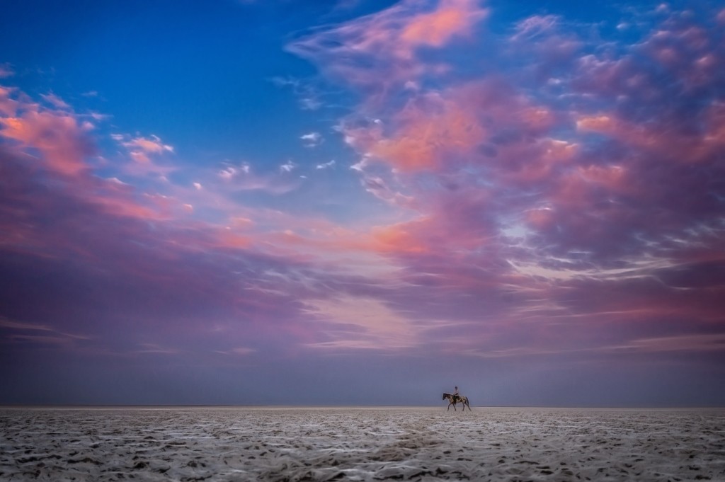 A lone rider on the dry salt pans Makgadikgadi under a purple sky