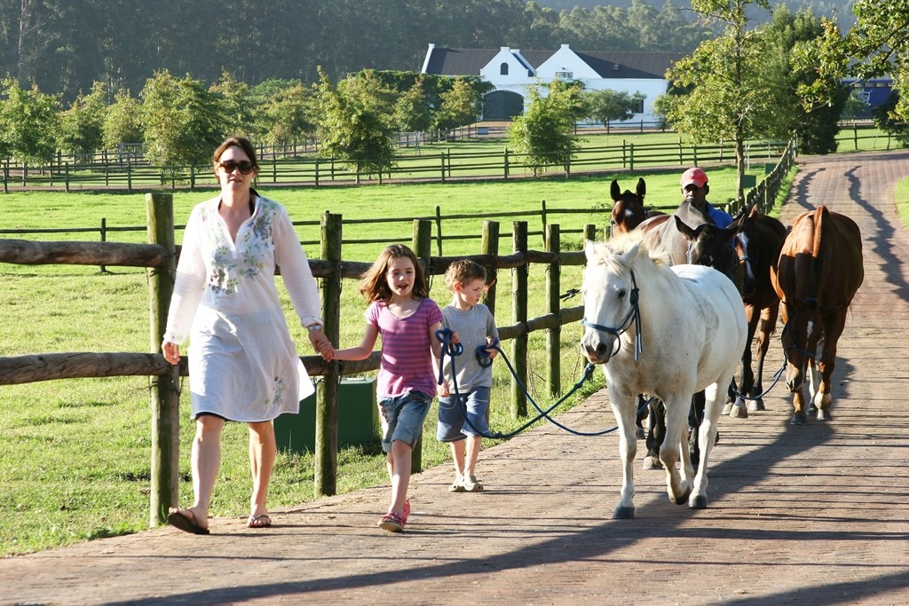 A family and guide walk the horses at Kurland, Garden Route, South Africa