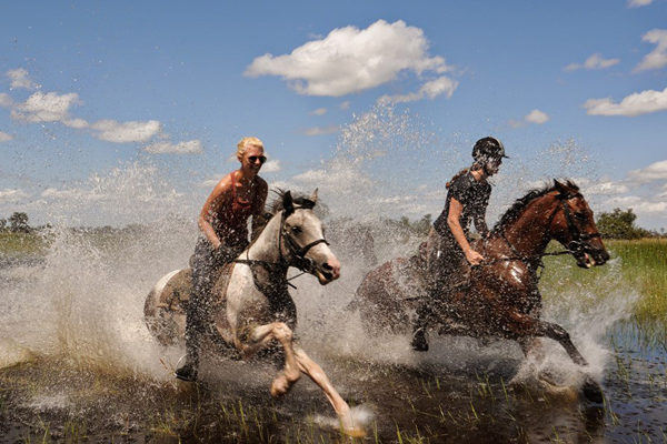 Riders splashing through the Okavango Delta, African Horseback safaris