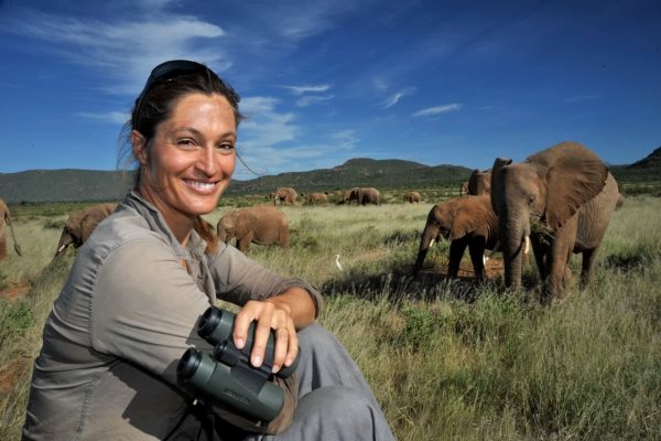 Saba Douglas-Hamilton -elephant guide with binoculars and elephants in the background