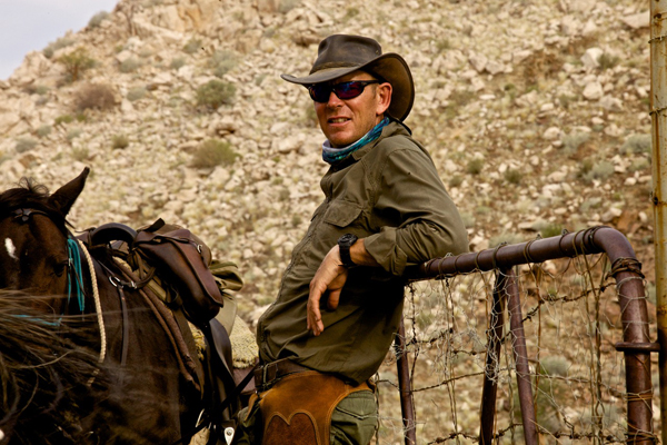 Riding guide Andrew Gillies with horse leaning on a gate, Namibia Horse Safaris