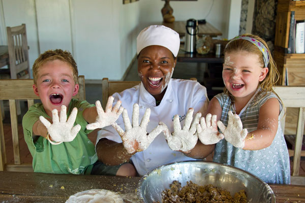 Children with messy baking hands at Anderssons Camp Namibia with babysitter