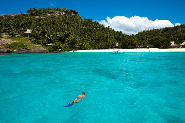 Seychelles outer islands man snorkelling in blue sea with Denis Island beach in background